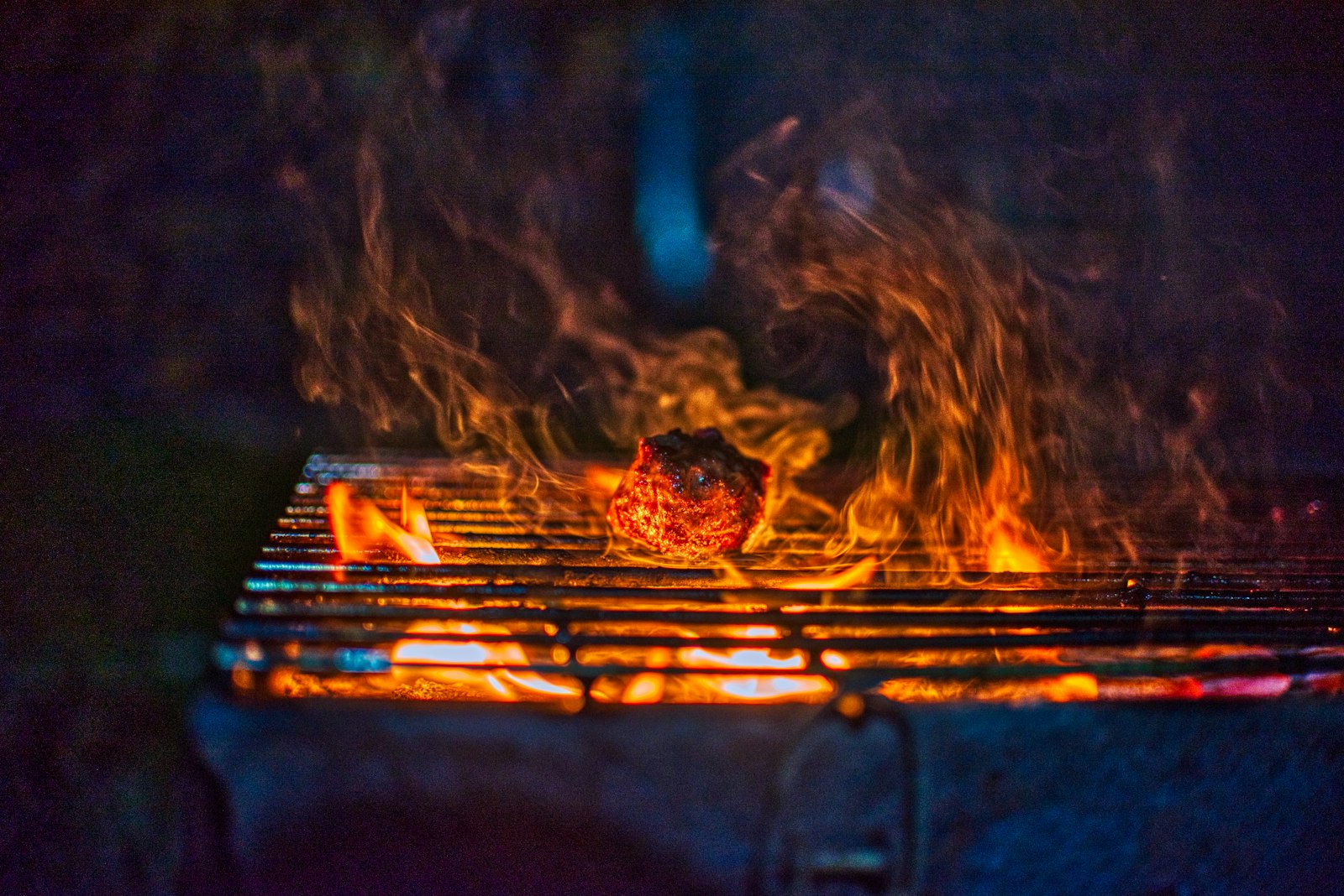 Braises et flammes vives sur la grille d'un barbecue au charbon