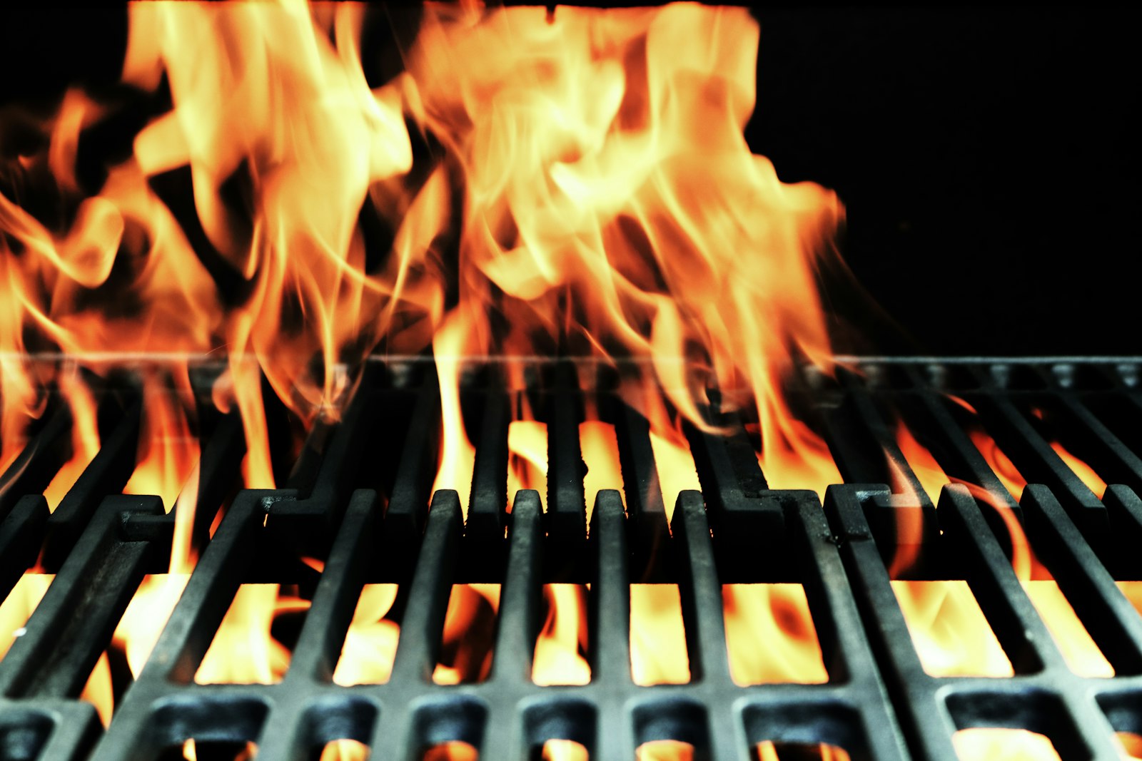 Grandes flammes s'élevant entre les barreaux de la grille d'un barbecue