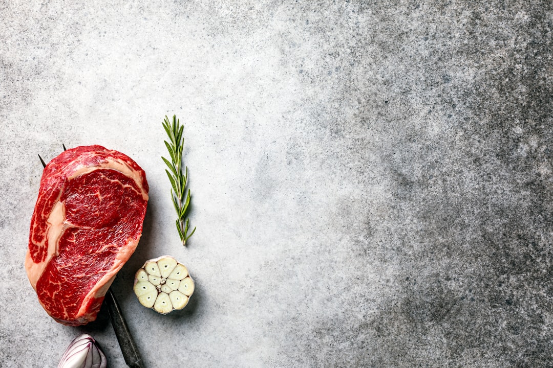 Côte de bœuf épaisse en train de saisir sur la grille d’un barbecue, marquée par la chaleur des braises.