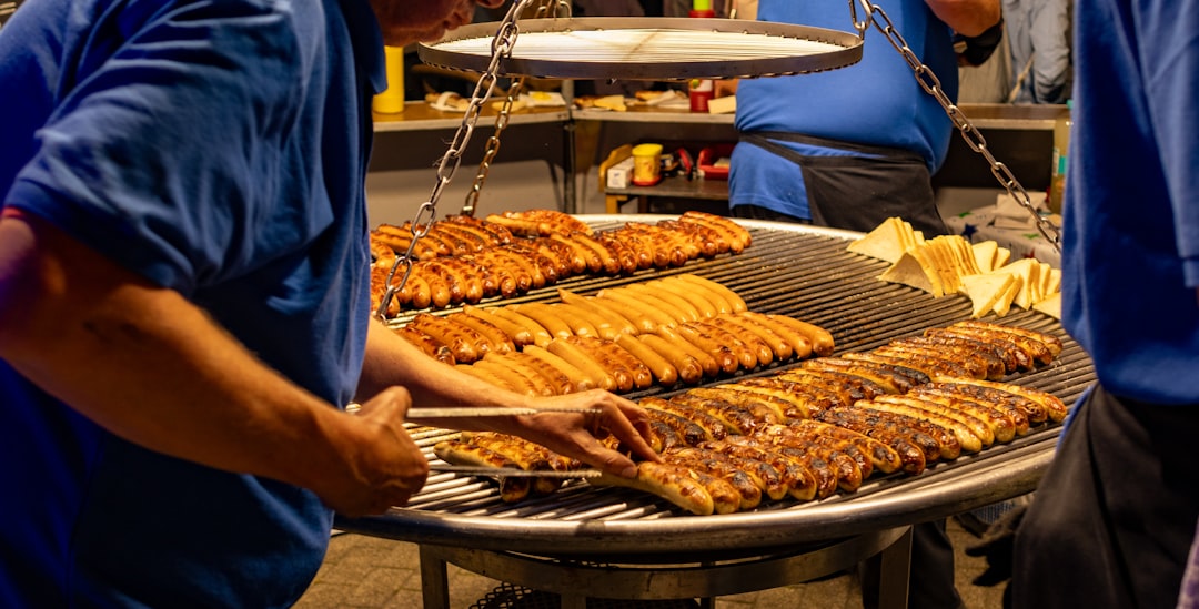 Pince à barbecue en inox tenue au-dessus d'une grille chaude, prête à retourner une pièce de viande.