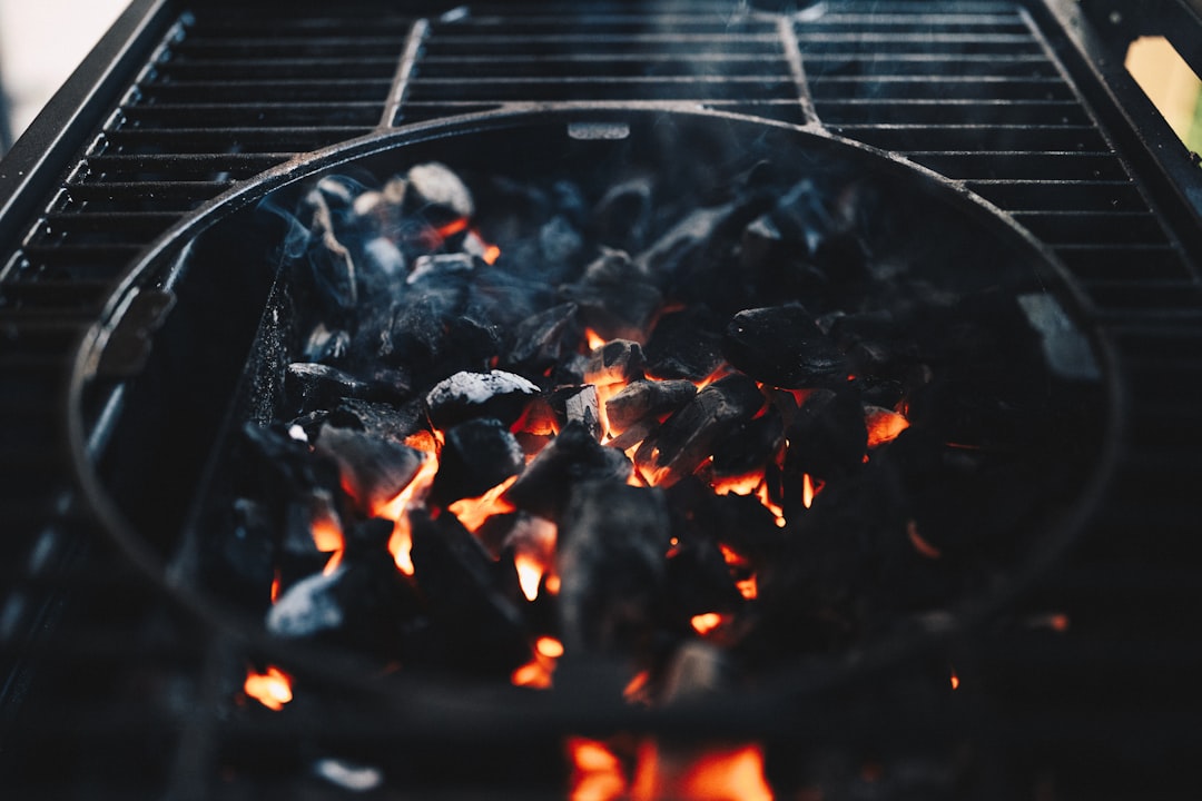 Plaque de plancha posée sur un barbecue au charbon, avec des aliments en cours de cuisson.