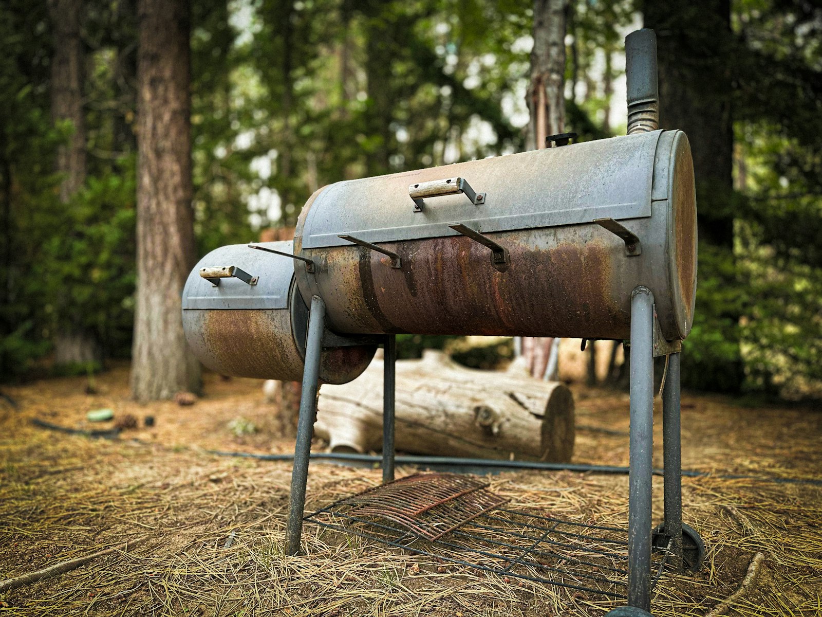 Fumoir offset en acier installé en extérieur, près des arbres